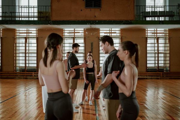 Group of people practicing rhythmic movements in a modern gym.